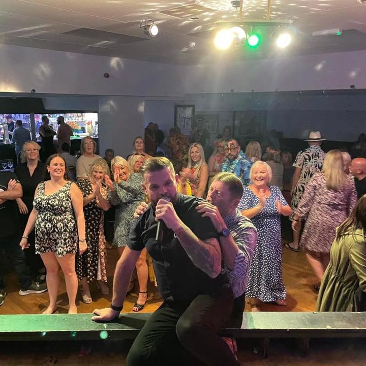 A lively crowd enjoying a performance, with a performer at the forefront.